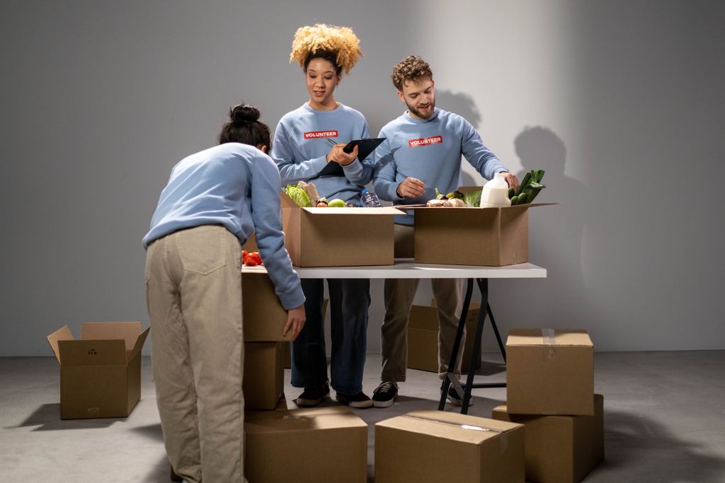 Three volunteers organizing food donations into boxes, showing teamwork and community support.
